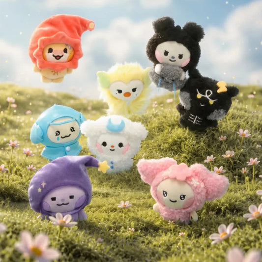 Colorful plush toys with animal-like designs on a grassy field with flowers and a blue sky.