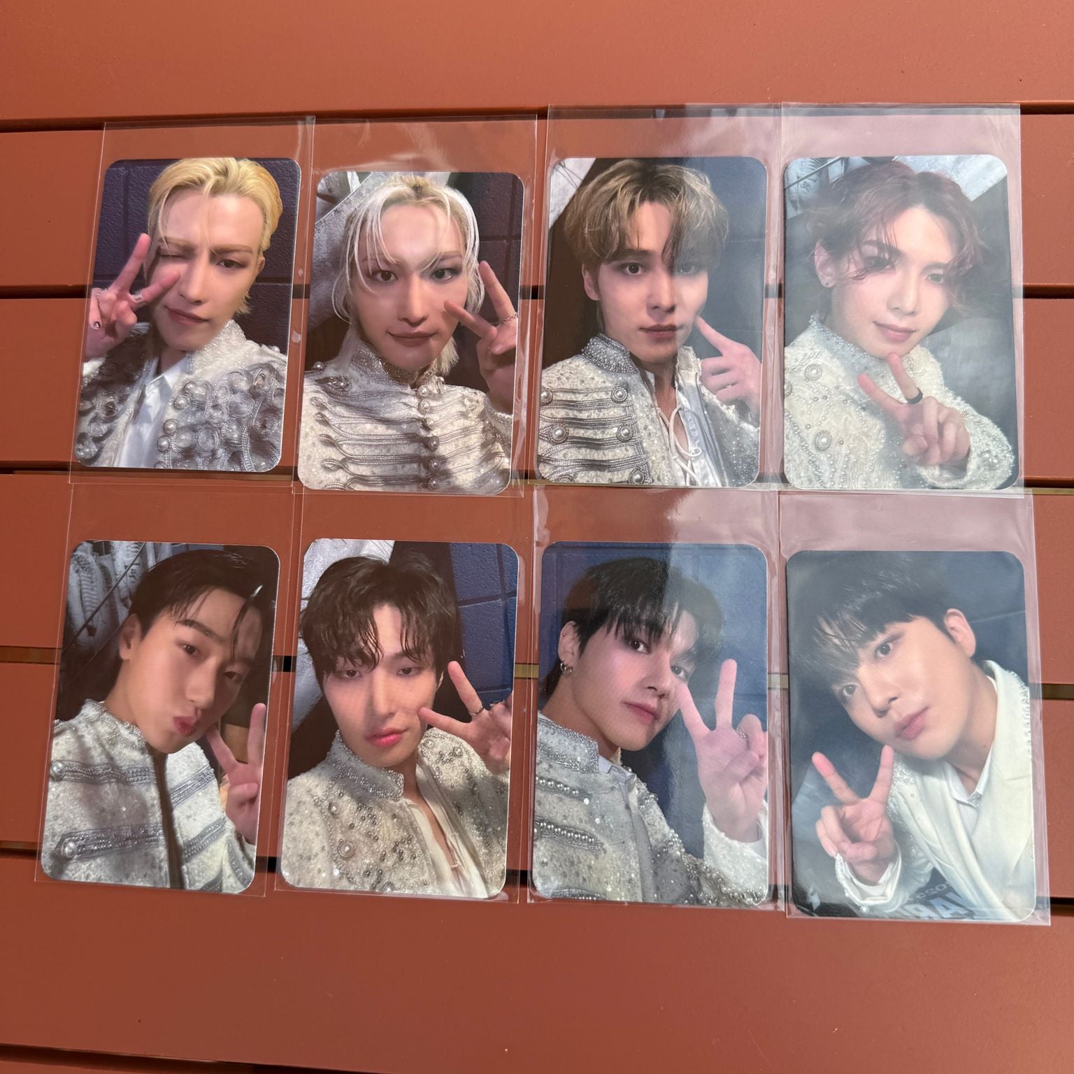 Collage of multiple photocards of kpop group ateez on a wooden surface