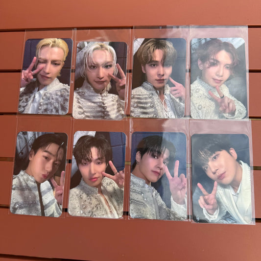 Collage of multiple photocards of kpop group ateez on a wooden surface